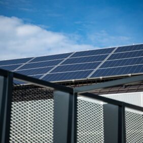 Een afbeelding van zonnepanelen op een dak tijdens een onweersbui met donkere wolken op de achtergrond.